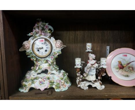 A Sitzendorf porcelain mantel clock and stand, 37.5cm high; together with another Sitzendorf figural three branch candlestick