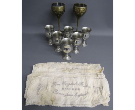 Pair of Brass goblets with peacock design, 6 Tudric pewter ware goblets and 5 cloths