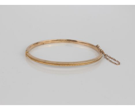 A 9ct gold bangle with safety chain - with herringbone decoration, internal size 58 x 49 mm, 4.6g.