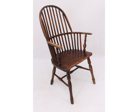 An early 19th century beech and elm hoop back Windsor arm chair - the high stick back over curved elm arms on curved supports