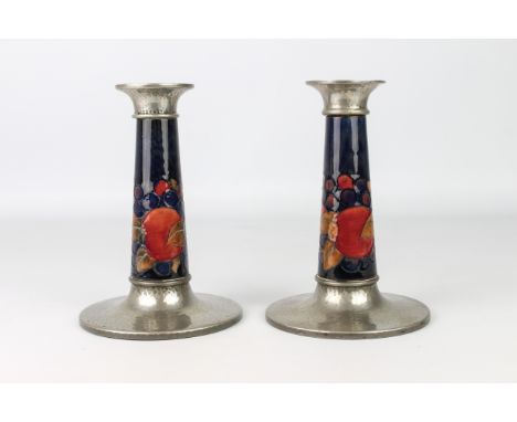 A good pair of William Moorcroft for Liberty &amp; Co. Tudric candlesticks - in the 'Pomegranate' pattern, impressed 'Made in