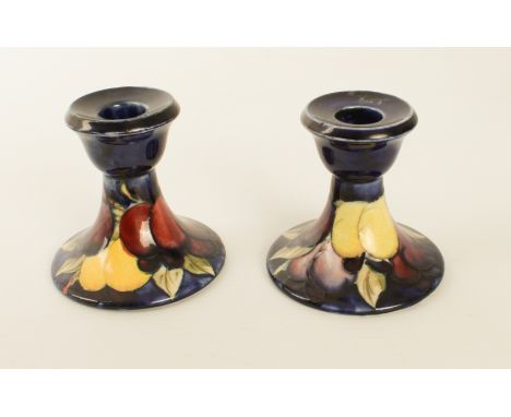 A closely matched pair of Moorcroft dwarf candlesticks in the 'Wisteria' pattern - impressed factory marks and blue painted i