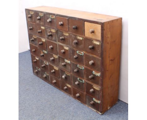 An early 20th century pine and beech wood 30-drawer pharmacy or shopkeeper's cabinet - the majority of the drawers with the o