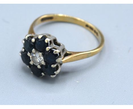 A 9ct. Gold Sapphire And Diamond Cluster Ring with a central diamond surrounded by sapphires, claw set, 3.2 gms., ring size M