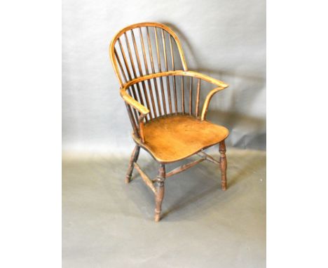 A 19th Century Elm Windsor Armchair, the spindle back above a panel seat with shaped arms, raised upon turned legs with stret