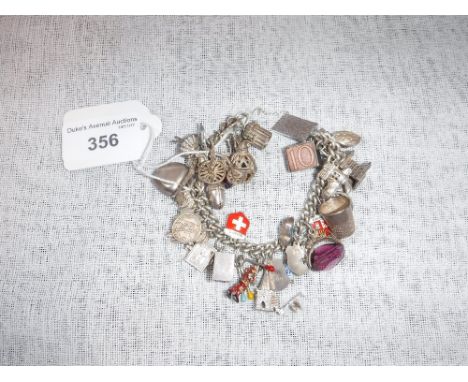 A VINTAGE SILVER AND WHITE METAL CHARM BRACELET with attached charms
