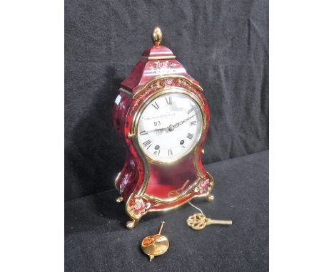 A ELUXA MANTEL CLOCK with white enamel dial and Roman numerals, the case with hand painted floral and gilt decoration on red 