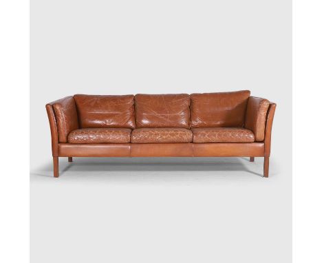 Stouby, a three-seater sofa, c.1970, Danish, with tan leather upholstery and raised on short, square, teak supports, 200cm wi