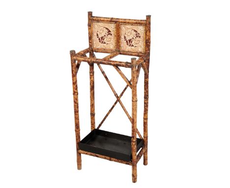 A 19TH CENTURY BAMBOO STICK-STAND each of the bamboo ends with pressed brass covers, with a floral tiled back and an associat