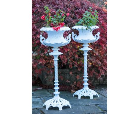 A PAIR OF COALBROOKDALE STYLE CAST IRON JARDINIERE the planters of urn form with moulded top edges and cherub figured handles