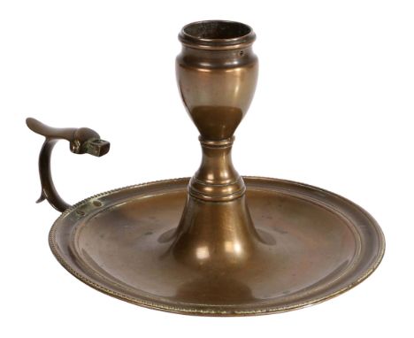 A George III reddish-brass chamberstick, circa 1780-90  Having an urn-shaped socket, a domed and circular pan with beaded rim