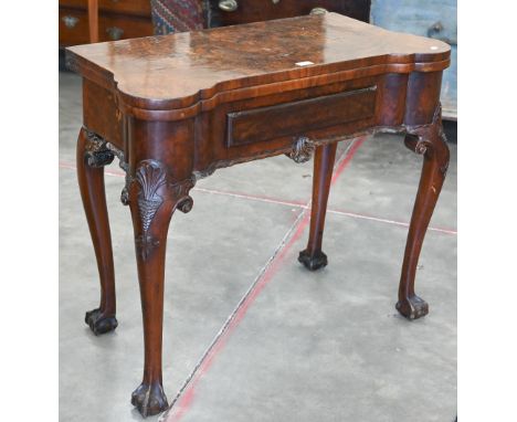 A George II style figured walnut gate-leg card table, the shaped baize lined folding top over a single frieze drawer raised o