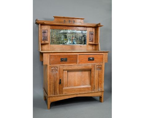 An early 20th century Arts &amp; Crafts mirror backed oak sideboard, the bevel edged plate flanked by pressed copper relief p
