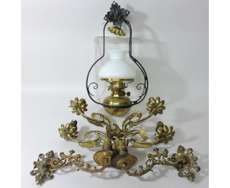 A hanging brass oil lamp, together with ornate brass wall lights and a pair of brass hanging lanterns, with white glass shade