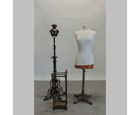 An early 20th century tailor's dummy, on an ornate cast iron base, 140cm tall, together with an oil lamp, on a wrought iron b