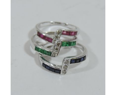 An 18ct white gold triple ring, with sapphires, emeralds, rubies and diamonds