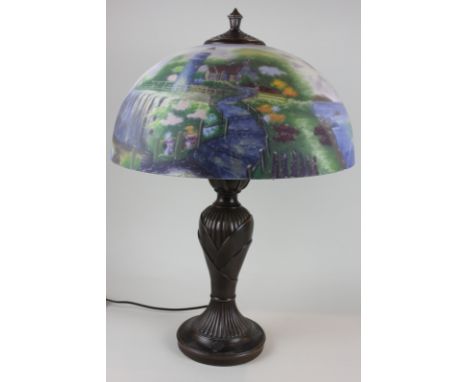 A bronzed metal table lamp with hand painted glass shade of lakeside scene