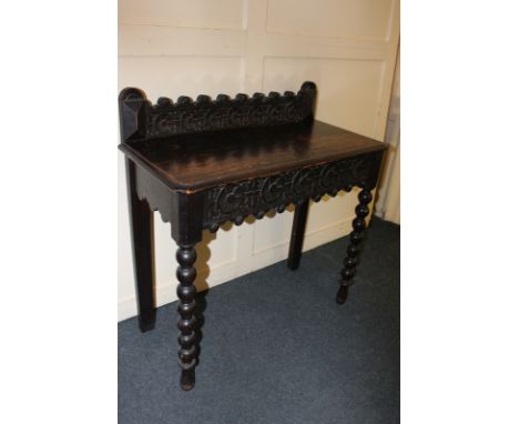 A carved dark oak galleried side table with single drawer, on turned legs