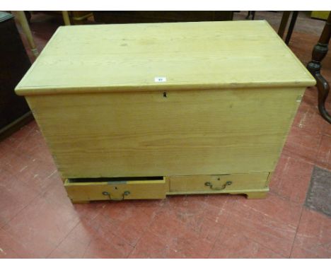 AN ANTIQUE STRIPPED PINE MULE CHEST with iron carry handles and twin lower drawers having swan neck handles on bracket corner
