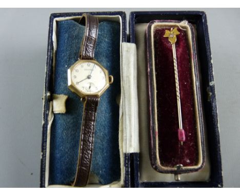 A NINE CARAT GOLD LADY'S WRISTWATCH with leather strap and a fifteen carat gold stick pin with small inset diamond