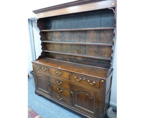 A GEORGE III OAK & PINE DRESSER, the three shelf wide boarded back plate rack with shaped sides on a two plank top over a 'T'