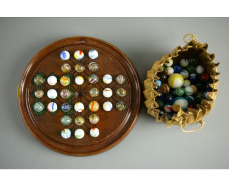 A VINTAGE WOODEN SOLITAIRE BOARD on squat bun feet with seventy eight ribbon core swirl and other decorative marbles