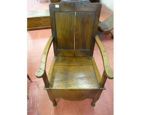 AN ANTIQUE OAK BOX SEAT ARMCHAIR with panel back and shaped apron, 101 cms high, 61 cms wide (interior base boards missing)
