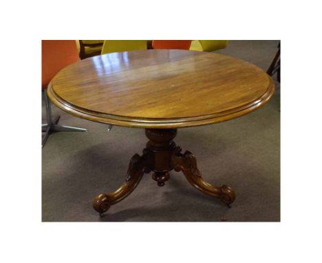 Mahogany framed circular topped breakfast table with turned column on a carved scrolling tripod base, raised on metal casters