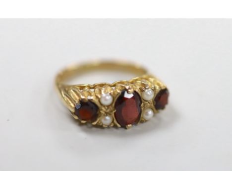 A 1970's 9ct gold, three stone garnet and four stone split pearl set half hoop ring, size K/L, gross weight 3.6 grams.