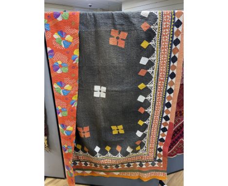 An early 20th century Indian multicoloured patchwork quilt, worked with a black central panel and ornate stripe bordered patt
