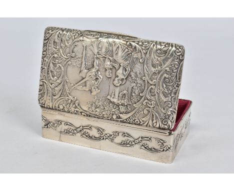 AN EDWARDIAN SILVER TRINKET BOX OF RECTANGULAR FORM, the hinged lid repousse decorated with a fete champetre and foliate scro