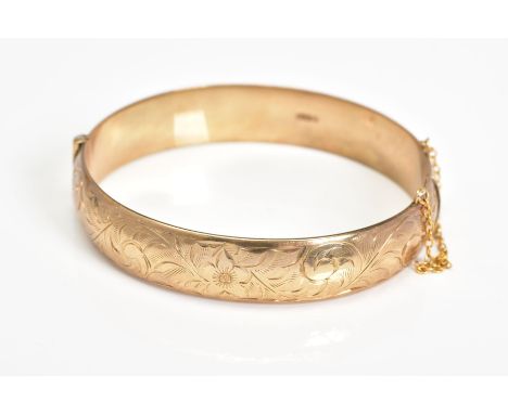 A MID TO LATE 20TH CENTURY 9CT GOLD OVAL BANGLE, half engraved in a floral and foliate design, hallmarked 9ct gold Birmingham