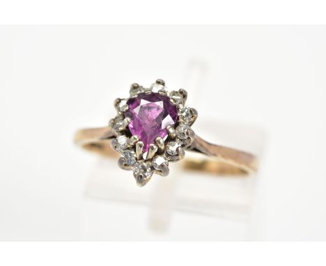 A 9CT GOLD RUBY AND DIAMOND RING, designed with a tiered pear cut ruby and single cut diamond surround to the plain polished 