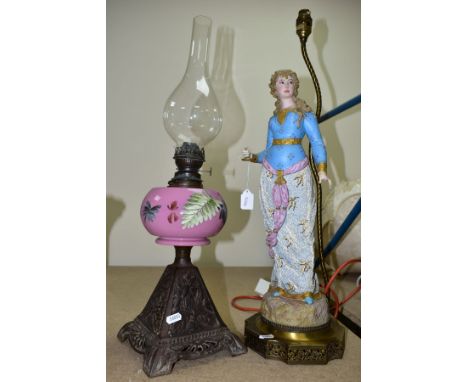 A SINGLE BURNER OIL LAMP, having pink glass reservoir decorated with foliate decoration and having cast metal base, impressed