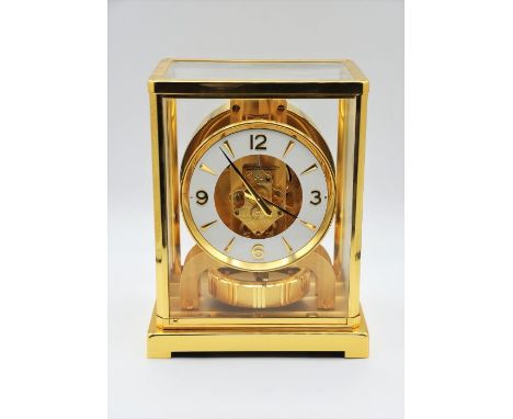 A Jaeger-LeCoultre Atmos clock, the white chapter ring with Arabic and baton numerals, in a polished lacquered brass and glas