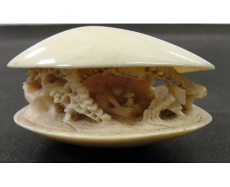 A Japanese Ivory Netsuke:
Meiji period
In the shape of a clam containing a landscape scene with two peasants under pine trees