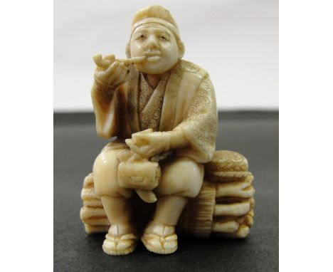 A Japanese Ivory Netsuke:
Meiji period
In the shape of a peasant smoking a pipe and sitting on a bundle of twigs. Artist's si