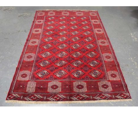 An Afghan bokhara carpet, late 20th century, the claret field with overall guls, within a wide sunburst gul border, 245cm x 1