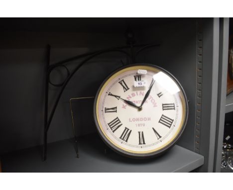 A reproduction Kensington Station clock with integral bracket, having Roman hours, 26cm diameter