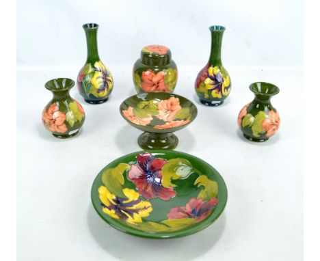 MOORCROFT; seven tubeline decorated 'Hibiscus' pattern pieces comprising a pair of bottle vases, height 21.8cm, a pair of bal