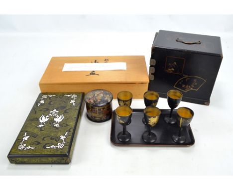 A group of lacquered items including a jewellery box with three drawers, width 19cm, and a set of six liqueur cups and a call