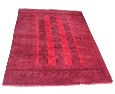 A large red ground Bokhara carpet with central field set with three rows of elephant foot medallions within a stylised border