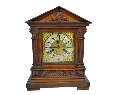 An early 20th century German mantel clock with brass base and silvered chapter ring set with Roman numerals, flanked by Corin