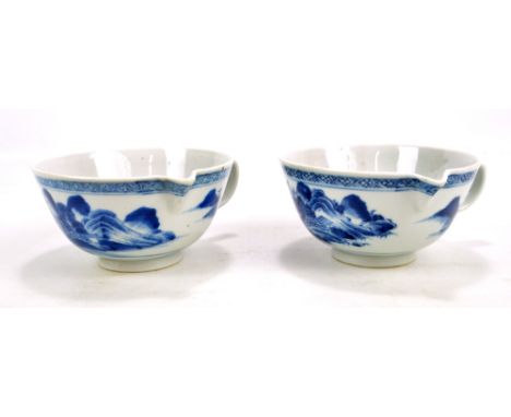 A near pair of Chinese porcelain vessels with beaks and loop handles to one side painted in underglaze blue with continuous a