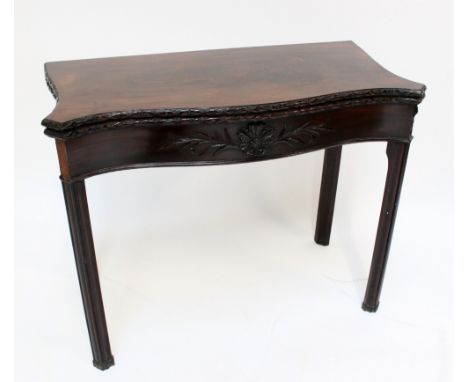 A George III mahogany serpentine card table with carved rim, applied carved detail to the frieze and chamfered legs, undersid