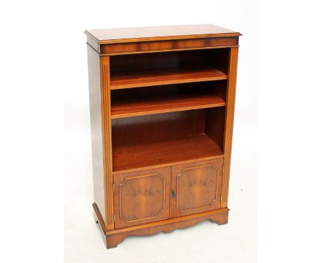 A reproduction yew wood open bookcase with two adjustable shelves above a pair of doors, on bracket feet, width 81cm, height 