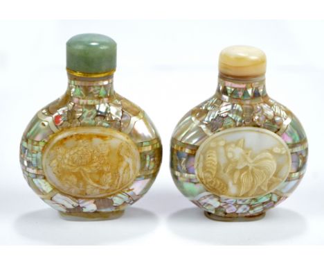 A near pair of Chinese mother of pearl veneered snuff bottles of flat globular forms, one centred with an oval carved floral 