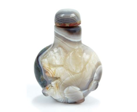 A Chinese white, grey, black and moss agate snuff bottle of flat globular form carved with boy playing with ball to one side,