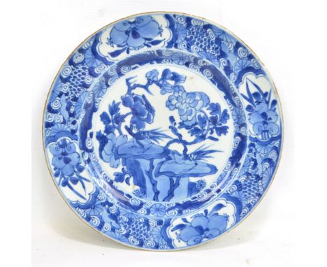 A Chinese porcelain circular plate painted in underglaze blue with birds perched on rocks amongst blossoming branches within 