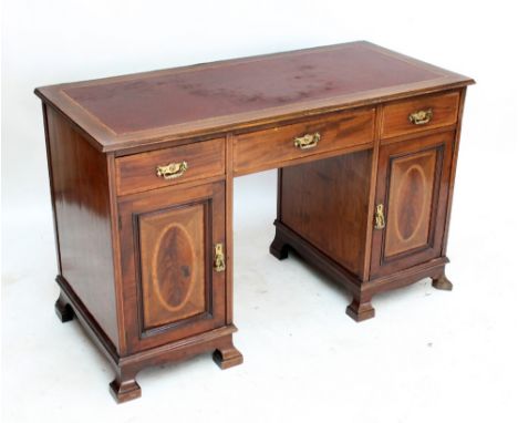 An Edwardian mahogany and inlaid kneehole desk, the moulded rectangular top above three frieze drawers, twin cupboard doors a